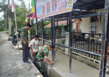 peran dalam kegiatan apapun, babinsa koramil 02/Bebesen bantu plester pagar kantor desa di wilayah binaan.